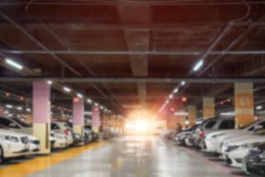 Blurry of car parking lots at shopping mall store with orange sun light.